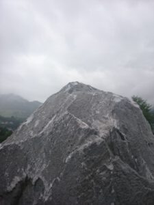 Ein Wolkenverhangener Himmel, im Vordergrund ist ein Fels